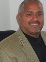 Kim Douglas, male with grey hair wearing tan blazer with a black shirt